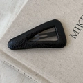 Detailed macro view of black faux crocodile leather triangle hair clip on beige book - Black Large Triangle Style