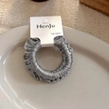 Detalle de un coletero de satén gris claro en un plato blanco con tarjeta de marca - Serie Azul Gris