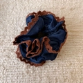 Dettaglio di elastico per capelli in denim blu con pizzo marrone su maglia beige - Modello Avvitato
