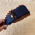 Dettaglio di cerchietto in denim blu con pizzo all'uncinetto marrone e fiocco elegante - Cerchietto