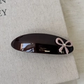 Macro detail of French style acetate barrette with pink bow and rhinestone on linen - Brown