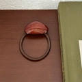 Detail of a brown elastic hair tie with a tortoiseshell resin charm on a wooden table - Brick Red