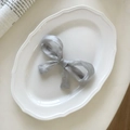 Close-up of elegant silver-grey organza bow hair clip on a decorative white porcelain plate - Silver