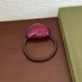 Detailed shot of a burgundy triangular resin hair tie with gold handmade lettering - Dark Red