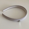 Gros plan d'un serre-tête en tissu gris clair avec un petit pendentif coeur en argent - Khaki