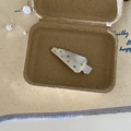 Fermaglio in metallo spazzolato argento con pois colorati su sfondo minimalista - Stile Forma Triangolare