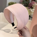 Primer plano de diadema rosa plisada con fina textura vertical y diseño de banda ancha - Rosa