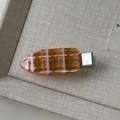 Detailed view of an orange and white checkered hair clip with gold glitter finish - Orange