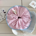 Detail of pink striped scrunchie with red dots and a blue border in a white ceramic dish - Pink
