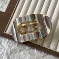 Detailweergave van de holle ovale haarklem met elegante crème en grijze strepen - Blauwgrijs