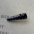 Close-up of a minimalist black hair clip with white polka dots on a linen fabric background - Black Triangle