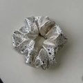 Detailaufnahme von cremefarbenem Samt-Haargummi mit funkelnden Kristallen und Strass - Off-White Haargummi