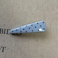 Detailed macro view of light blue triangular hair clip with dark brown polka dots - Blue Triangle