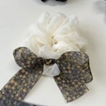 Detailed view of white organza scrunchie with a dark floral bow and sheer pleated texture - Off-white Scrunchie