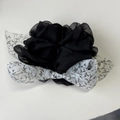 Detail of black chiffon scrunchie with a floral print bow showing fabric texture - White Bow Black Scrunchie