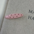 Close-up of a pink oval hair clip with brown polka dots on a natural canvas surface - Pink Oval Hair Clip