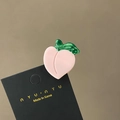 Detail of a peach-shaped acetate hair claw clip with green leaf on a display card - Peach