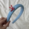 Détail d'un serre-tête à carreaux bleus avec nœud rouge et étiquette gravée LOVE - Serre-tête à Carreaux Bleu