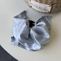Detail of elegant silver-blue satin hair claw clip showing silky fabric texture on desk - Blue