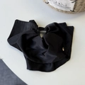 Detail of large black satin bow hair claw clip showing elegant fabric folds and metal buckle - Black