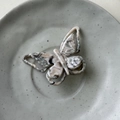 Detail view of the colorful acetate butterfly hair clip showing marble texture and metal teeth - Grey-Beige