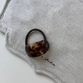 Detail of tortoiseshell acetate hair tie with dark brown elastic band on linen - Curved Elastic Band