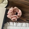 Detailed view of pink chiffon scrunchie with white piping on a warm wooden background - Pink
