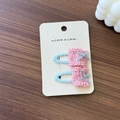 Close-up of pink lace hair clips with blue bows on a card over a wood background - Blue