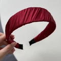 Detailed view of the pleated silk fabric texture on a wine red French wide headband - Red