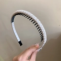 Close-up of beige woven fabric headband with non-slip black plastic inner teeth detail - White
