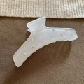 Close-up of frosted resin hair claw with yellow rhinestones on dark fabric background - White