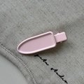 Primer plano de pinza geométrica rosa para el cabello con acabado mate sobre lino - Rosa
