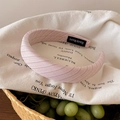 Detail eines rosa gepunkteten Stirnbandes mit Webstruktur und handgemachtem Etikett - Diagonalmuster