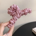 Detailansicht der plissierten rosa Satinstoff-Textur auf der eleganten Haarklammer - Rosa