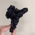 Close-up of black pleated fabric flower hair claw clip with a subtle glossy finish - Black