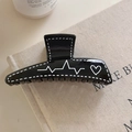 Dettaglio molletta nera per capelli con graffiti a cuore bianco su sfondo beige - Nero