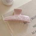 Dettaglio ravvicinato della molletta rosa con motivo a cuore su tela beige - Rosa