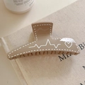 Dettaglio del fermaglio a trapezio con cuore bianco su sfondo in lino beige morbido - Caffè Chiaro