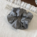 Detail eines grau gestreiften Haargummis mit Leinentextur auf Spitzenhintergrund - Scrunchie / Grau