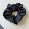 Dettaglio di un elastico per capelli in tessuto a coste grigio scuro con etichetta bianca - Nero