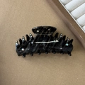 Close-up of black tortoiseshell hair claw clip with colorful rhinestones on brown background - Black