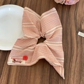 Dettaglio dell'elastico per capelli a quadretti arancioni con bottone rosso e etichetta - Rosa
