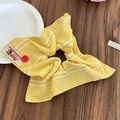 Dettaglio dello scrunchie a scacchi gialli con bottone rosso ed etichetta su legno - Giallo