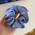 Macro shot of light blue scrunchie showing detailed denim texture and ruffled fabric folds - Denim Blue