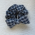 Detail view of a vintage plaid sponge bow scrunchie on a soft textured background - Grey Blue Plaid Bow