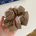Detailed view of large khaki scrunchie with pleated twill fabric texture and elastic design - Brown