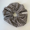 Close-up van een vintage ruitjes scrunchie met klassiek patroon en ingenaaid stoffen label - Khaki Raster