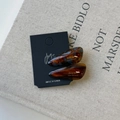 Close-up of tortoise shell acetic acid teardrop hair clips set with gold brand logo lettering - Brown Series