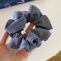 Detail shot of grey-blue twill fabric hair scrunchie with layered ruffle texture - Gray