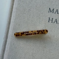Detail of tortoiseshell acetate hair clip with colorful rhinestones on a fabric background - Amber